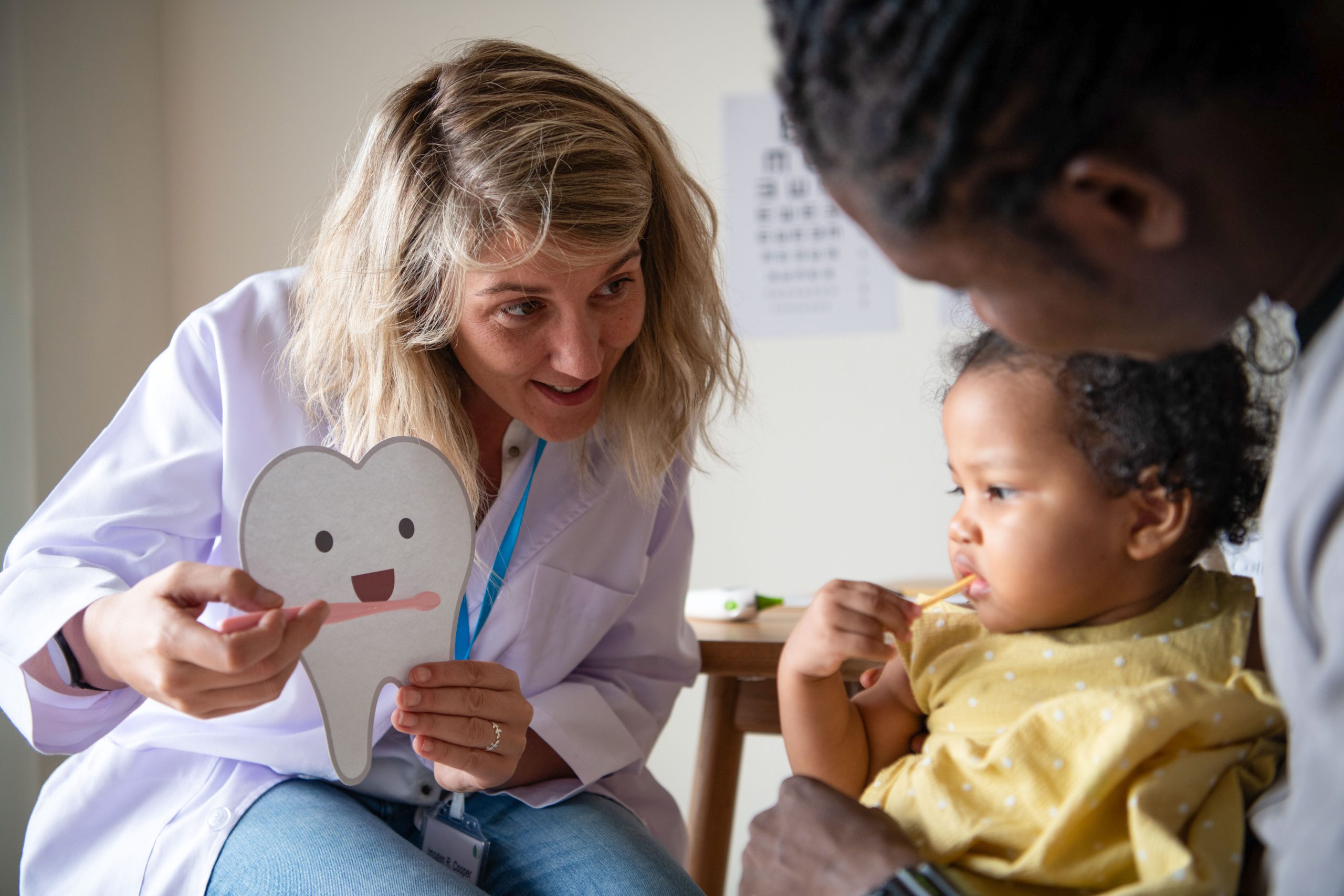 Odontopediatra realizando avaliação bucal em criança durante consulta preventiva para acompanhar o desenvolvimento dos dentes e da arcada dentária.